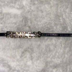 Taylor Swift Fearless gold charm bracelet on faux leather metallic strap.
